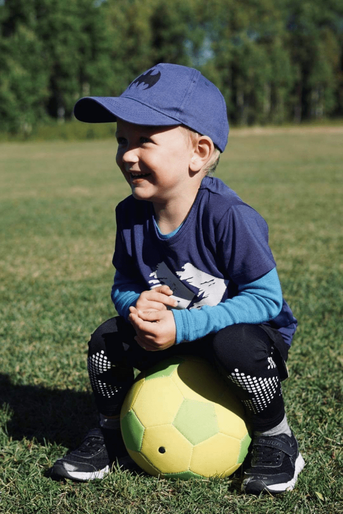 Ett barn sitter på en fotboll utomhus